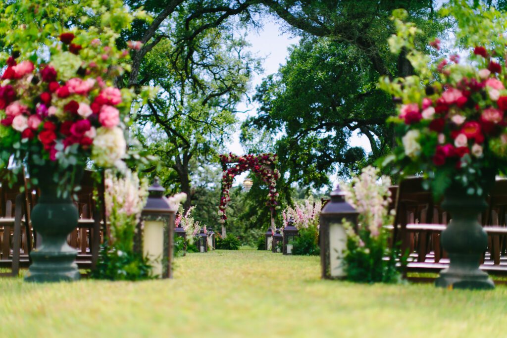 Garden ceremony aisle with floral arrangements and lanterns