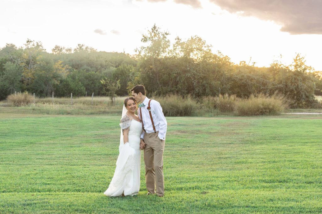 Couple embracing in open field during golden hour