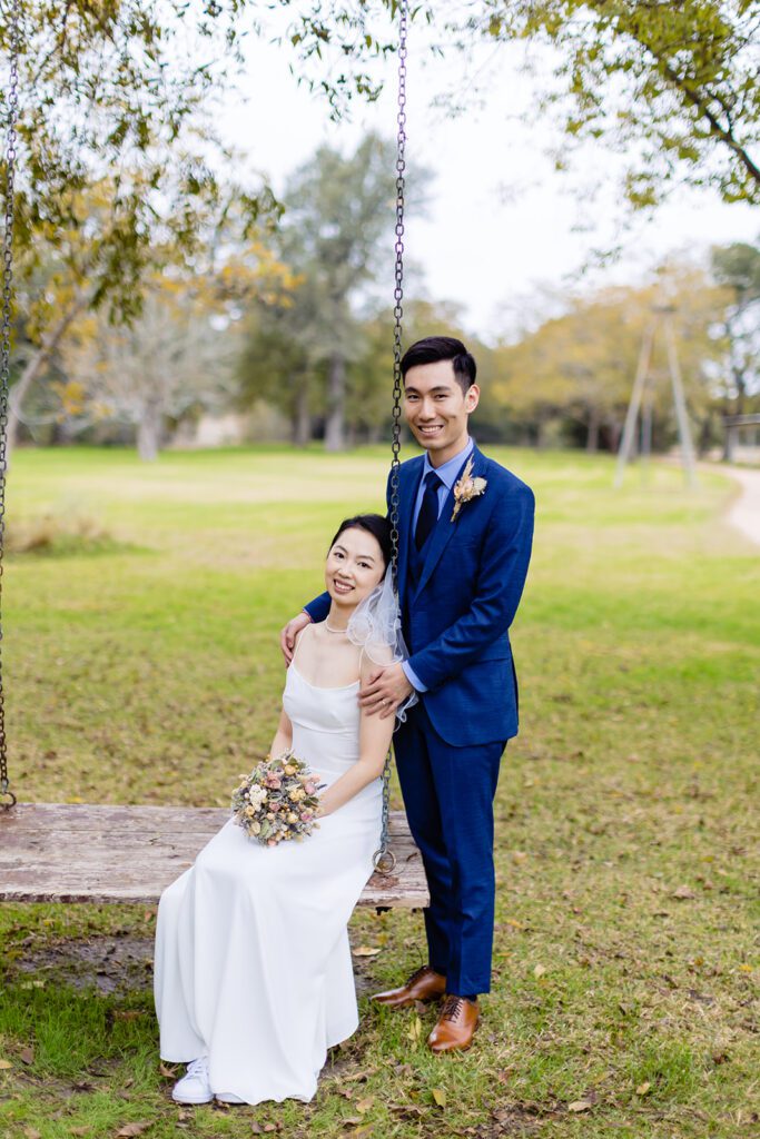 Couple posing on wooden swing in outdoor venue setting