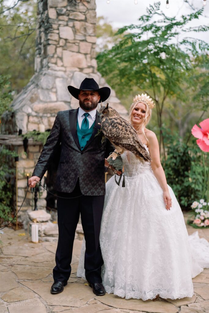Bride and groom posing with owl at outdoor ceremony