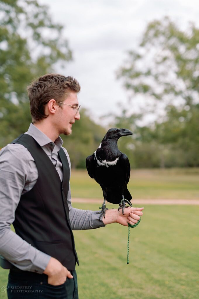 Man holding a raven outdoors