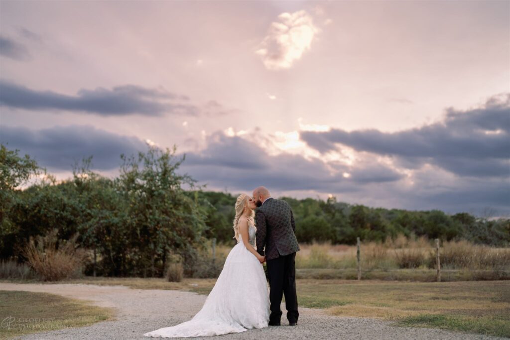Bride and groom kissing at sunset outdoors