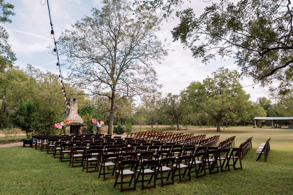 Outdoor wedding ceremony setup with wooden chairs and string lights