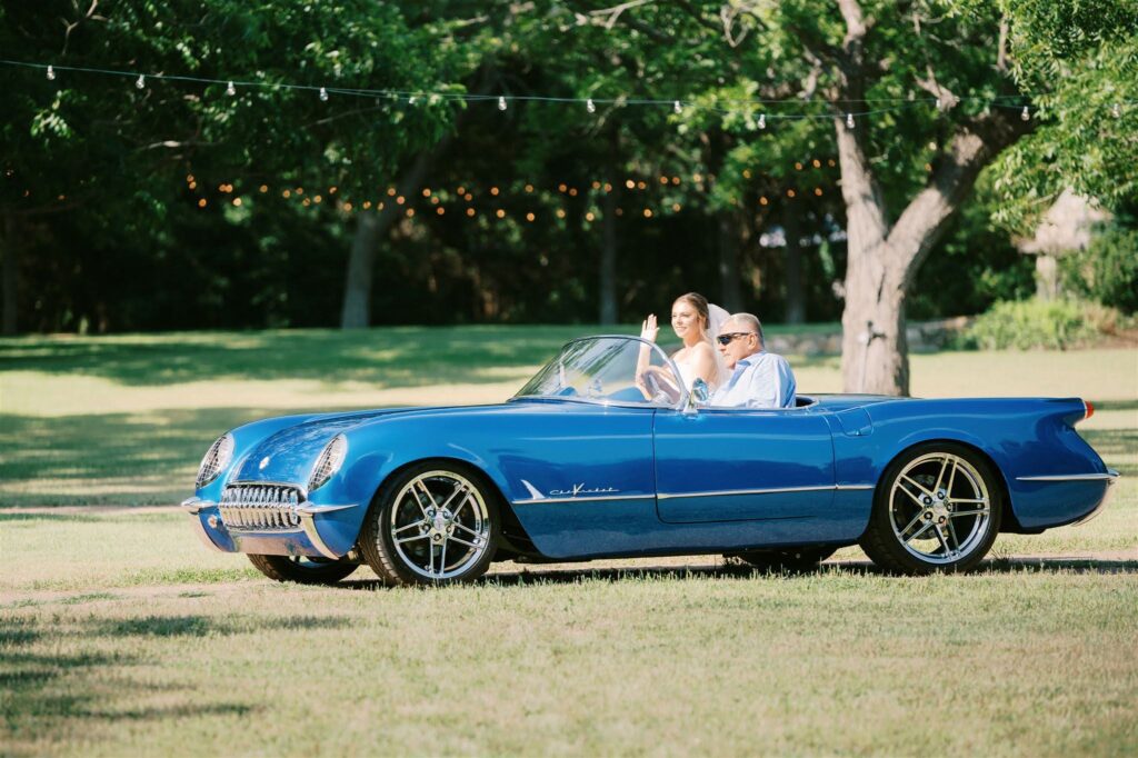 Bride riding in blue vintage convertible at venue