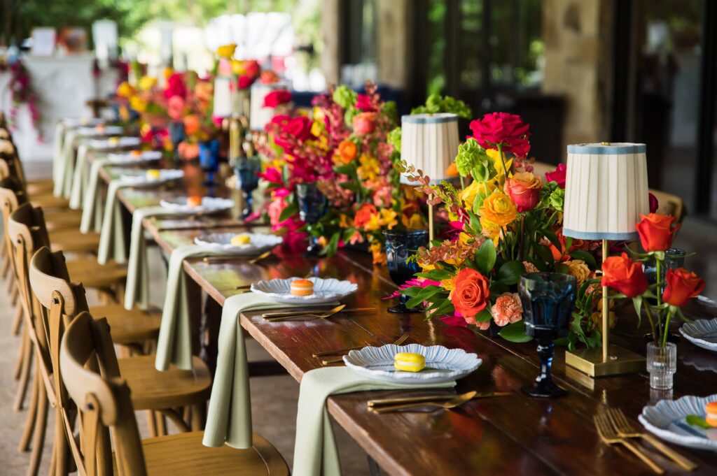 Long reception table with vibrant floral arrangements and place settings