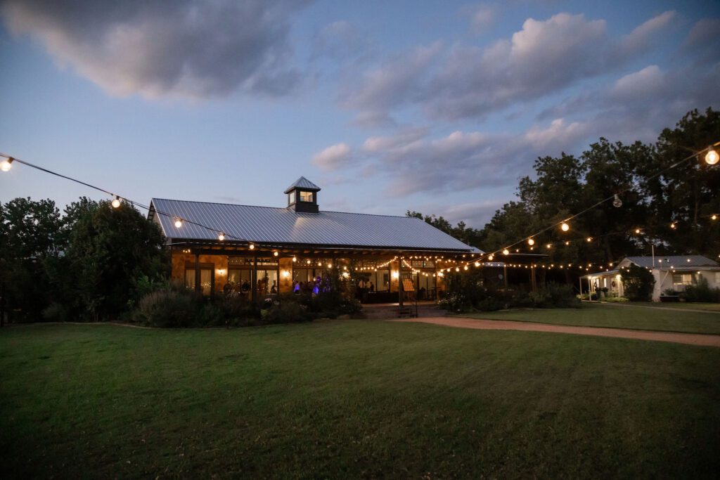 Outdoor venue at dusk with string lights and reception space