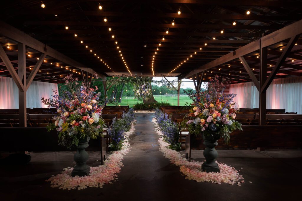 Indoor ceremony aisle with floral arrangements and romantic lighting