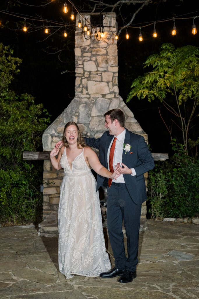 Newlyweds laughing by an outdoor fireplace