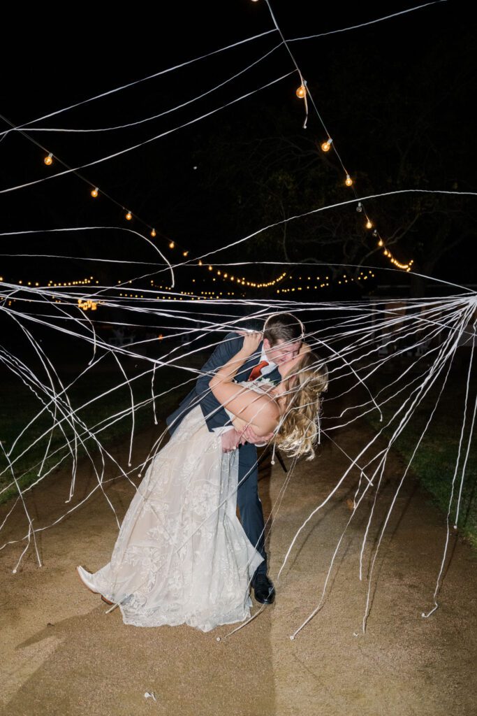 Newlyweds kissing beneath streamers
