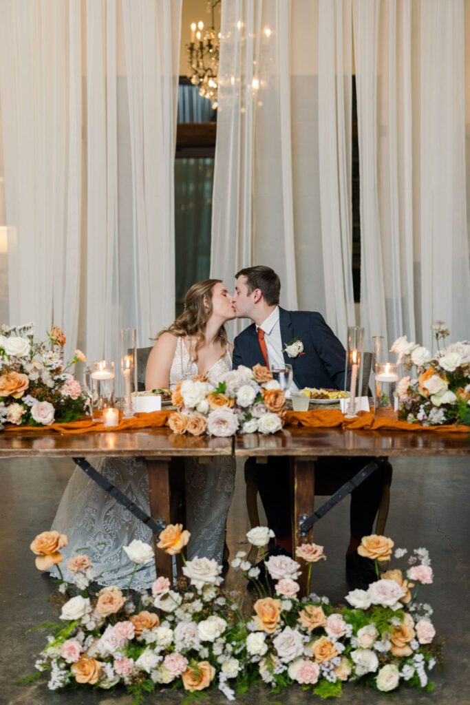 Newlyweds kissing at their sweetheart table