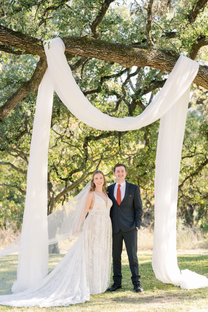 Bride and groom under a white ceremony drape