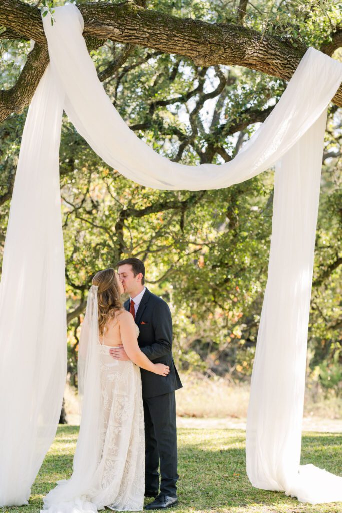 Newlyweds kissing beneath the ceremony drape