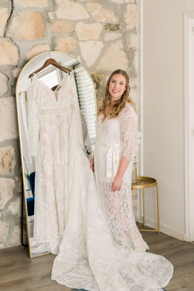 Bride standing beside her wedding dress