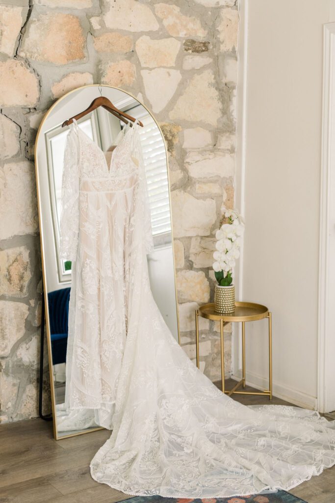 Lace wedding dress hanging by a mirror