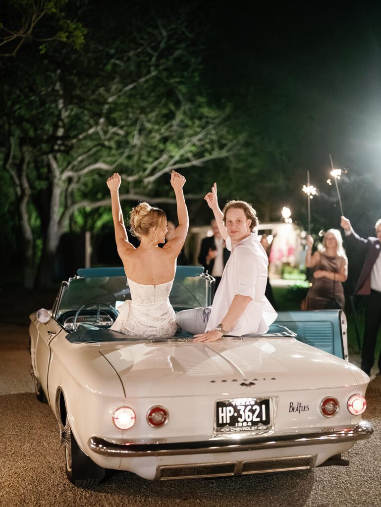 Newlyweds celebrating on vintage convertible