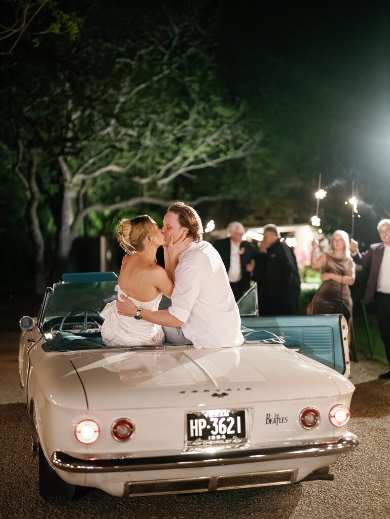 Newlyweds kissing on vintage convertible