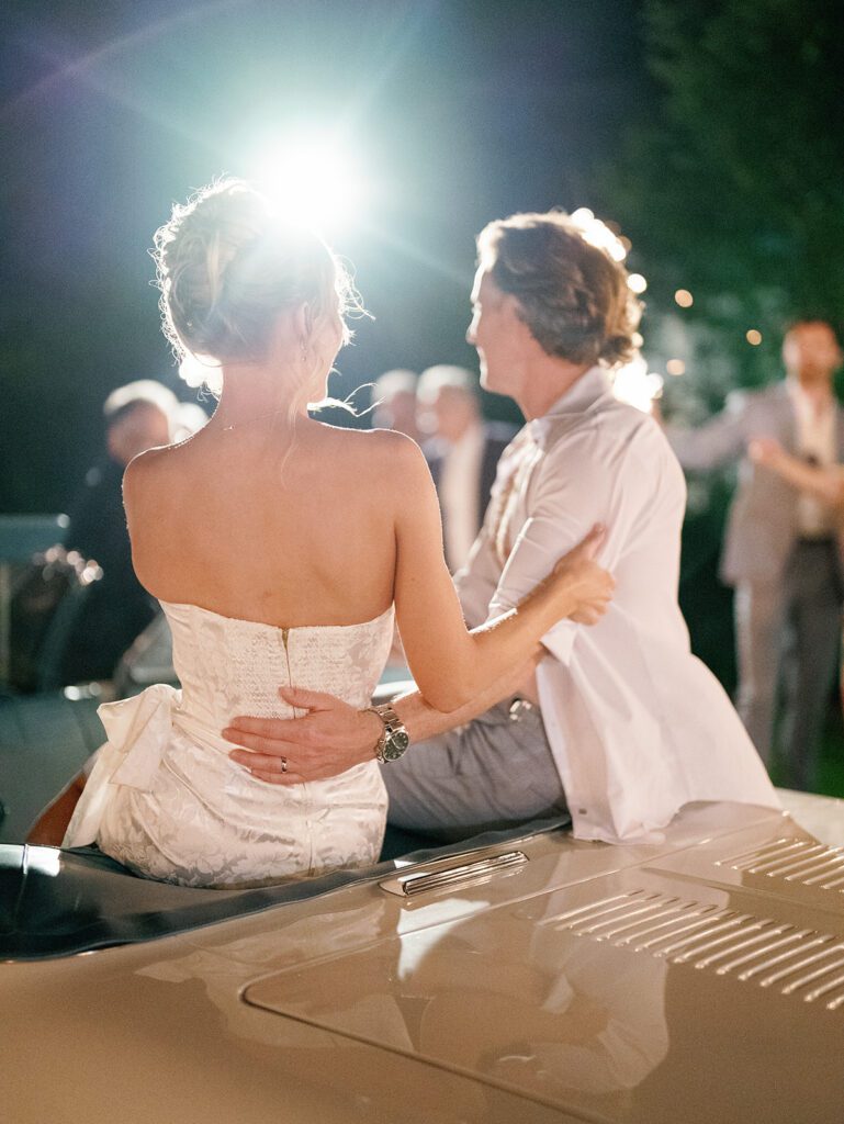 Newlyweds sitting together on vintage convertible