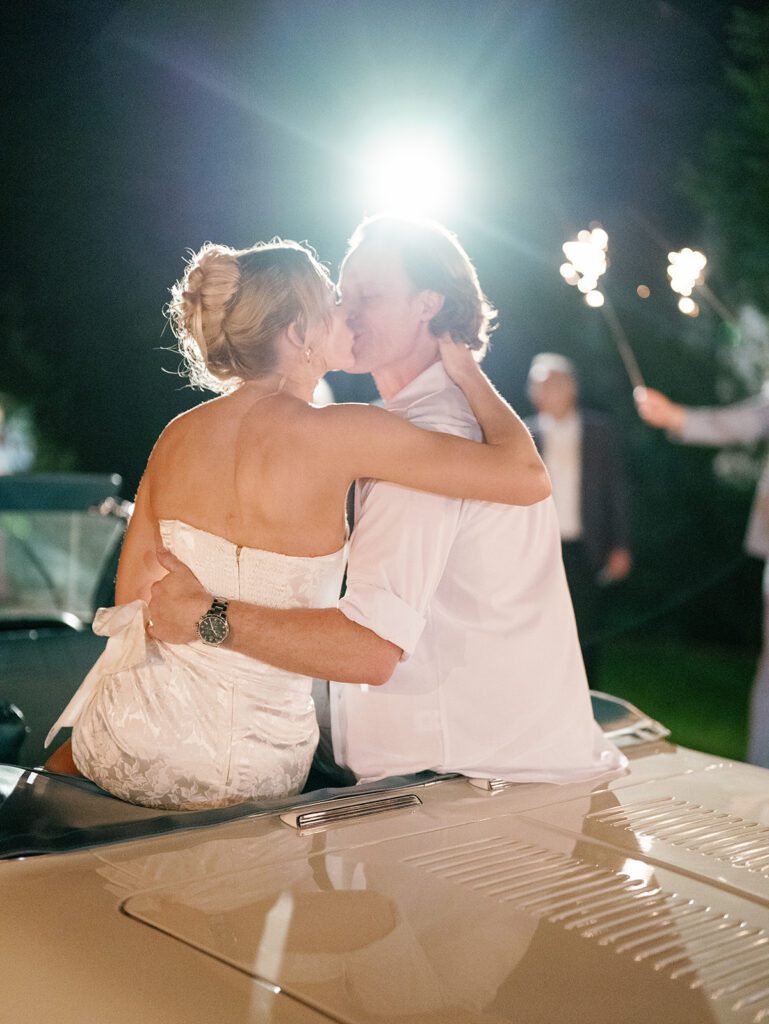 Newlyweds kissing on vintage convertible