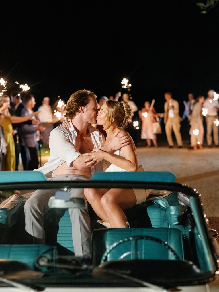 Newlyweds kissing while seated in convertible