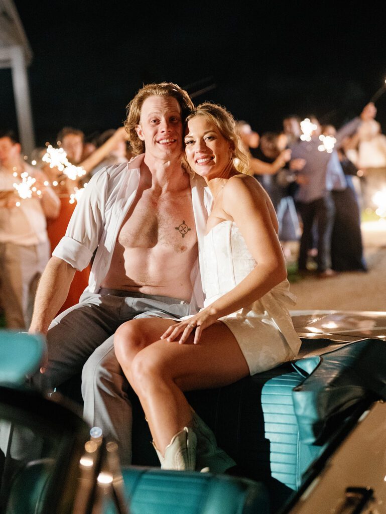 Newlyweds posing together in vintage convertible