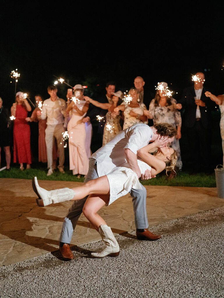 Newlyweds dipping and kissing during sparkler exit