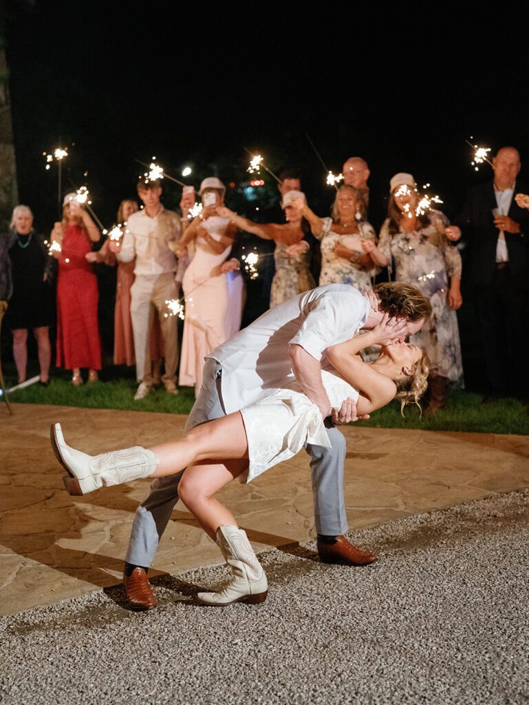 Newlyweds dipping and kissing during sparkler exit at Pecan Springs Ranch